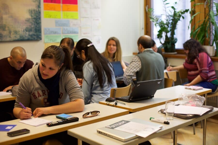 ihmiset opiskelevat pöytien äärressä