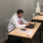 opiskelija istuu ja työskentelee tietokoneella